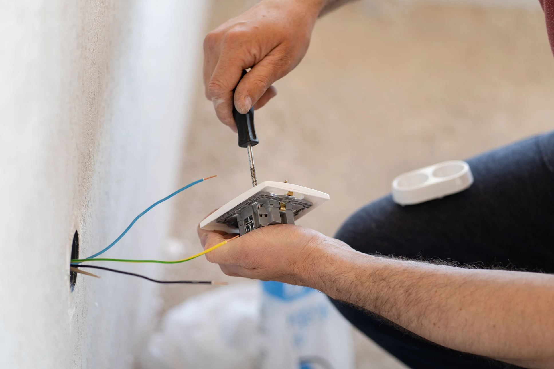 Électricien installant un interrupteur mural dans un intérieur résidentiel